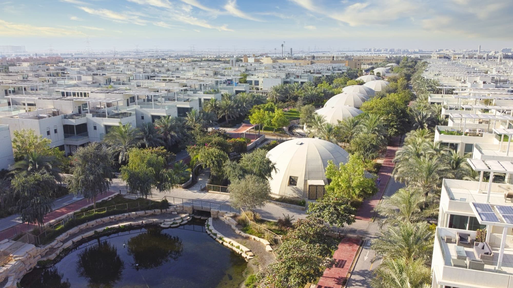 Aerial view of The Sustainable City in Dubai, its biodomes, lagoons and planted streets visible